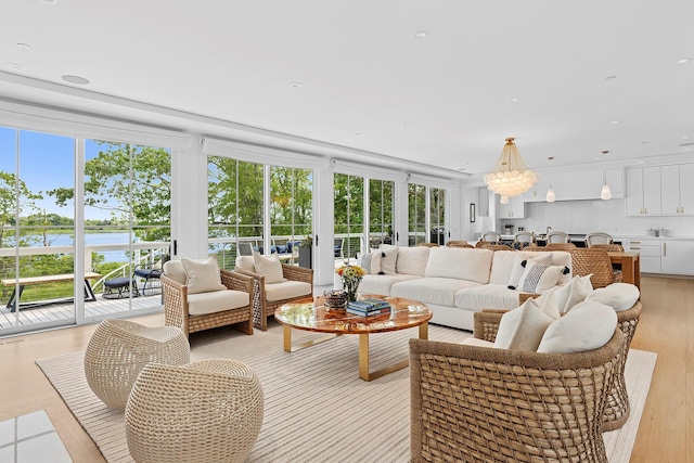 801 Montauk Hwy, Westhampton Beach, NY 11978 - living area featuring plenty of natural light, a water view, light wood-style floors, and a chandelier