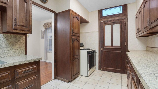 868 Morris Park Ave, Bronx, NY 10462 - kitchen with gas range gas stove, light countertops, decorative backsplash, light tile patterned flooring, and dark brown cabinetry