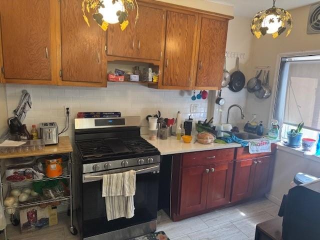 33-42 70th St, Jackson Heights, NY 11372 - kitchen featuring stainless steel range with gas cooktop, decorative backsplash, light countertops, and decorative light fixtures