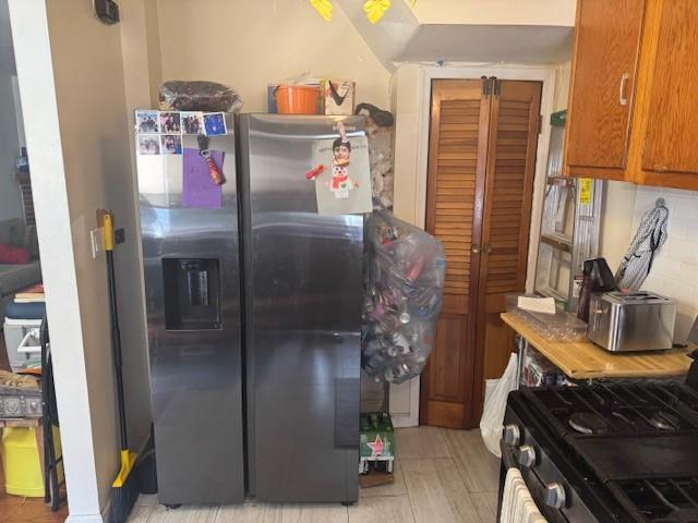 33-42 70th St, Jackson Heights, NY 11372 - kitchen featuring stainless steel fridge, gas range, brown cabinets, and light wood-type flooring