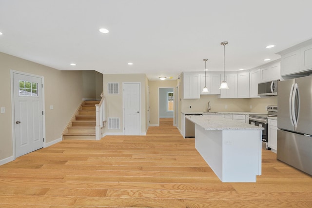 159 Mohawk St, Ronkonkoma, NY 11779 - kitchen featuring stainless steel appliances, white cabinetry, recessed lighting, light wood-style floors, and hanging light fixtures