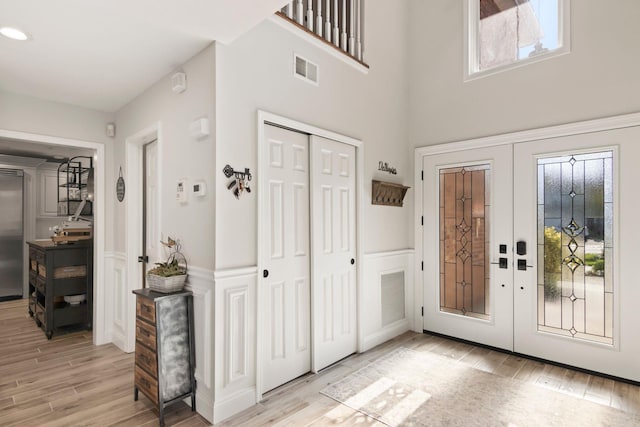 62 Hamlet Dr, Commack, NY 11725 - foyer entrance featuring french doors, healthy amount of natural light, light wood-style floors, a wainscoted wall, and a towering ceiling