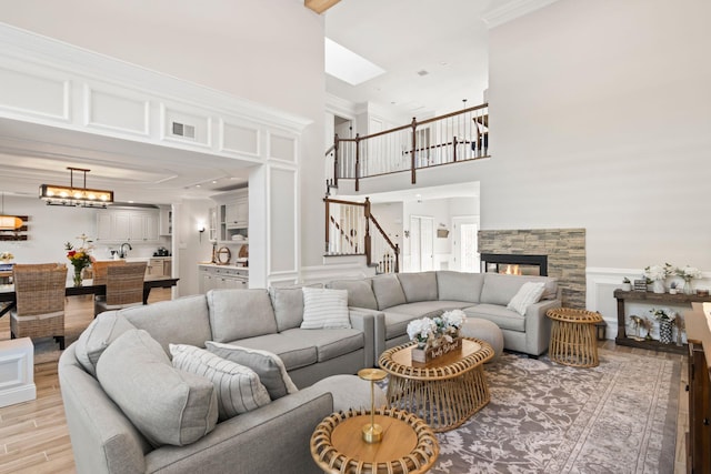 62 Hamlet Dr, Commack, NY 11725 - living room featuring light wood-style flooring, a towering ceiling, stairs, wainscoting, and crown molding