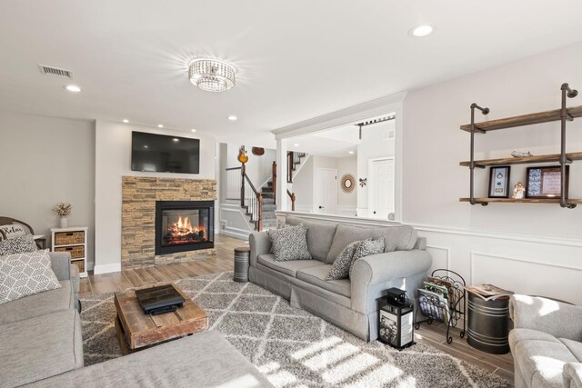 62 Hamlet Dr, Commack, NY 11725 - living room featuring wood finished floors, a stone fireplace, stairs, a wainscoted wall, and recessed lighting
