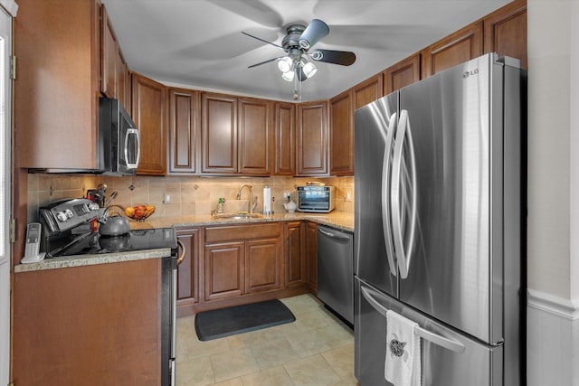 115 W Granada Ave, Lindenhurst, NY 11757 - kitchen featuring appliances with stainless steel finishes, brown cabinetry, backsplash, ceiling fan, and light stone counters