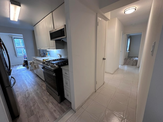 209-15 18th Ave Unit 2A, Bayside, NY 11360 - kitchen featuring appliances with stainless steel finishes, white cabinetry, light countertops, and light wood-type flooring