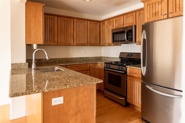 600 Clarence Ave Unit 2H, Bronx, NY 10465 - kitchen with stainless steel appliances, light wood finished floors, a peninsula, light stone countertops, and brown cabinetry