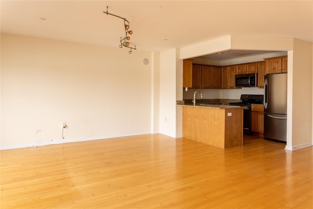 600 Clarence Ave Unit 2H, Bronx, NY 10465 - kitchen with stainless steel appliances, open floor plan, brown cabinetry, light wood finished floors, and a peninsula