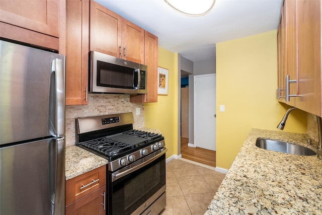 625 Gramatan Ave Unit 6L, Fleetwood, NY 10552 - kitchen with stainless steel appliances, light stone counters, light tile patterned floors, brown cabinetry, and tasteful backsplash
