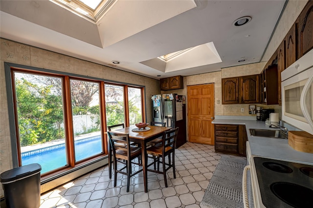 805 Arlington Rd, West Babylon, NY 11704 - dining space with a skylight, a baseboard heating unit, light floors, and a tray ceiling