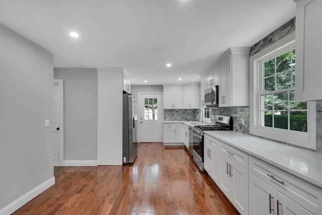 14 Sycamore St, Centereach, NY 11720 - kitchen with appliances with stainless steel finishes, backsplash, white cabinetry, light countertops, and dark wood-style flooring