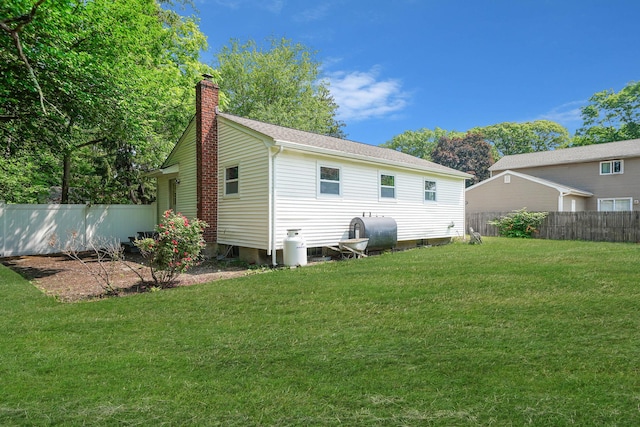 14 Sycamore St, Centereach, NY 11720 - back of house with oil tank, a chimney, and roof with shingles