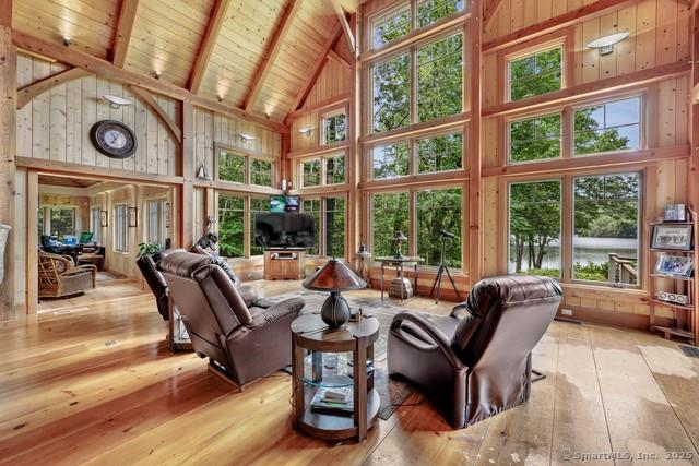 218 Kuhne Rd, Call Listing Agent, CT 06488 - living room featuring high vaulted ceiling, plenty of natural light, hardwood / wood-style floors, wood walls, and a wooden ceiling with exposed beams