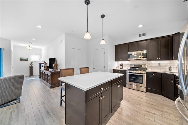 105 Captain S Way, Copiague, NY 11726 - kitchen featuring stainless steel appliances, light wood-style floors, light countertops, a kitchen bar, and recessed lighting