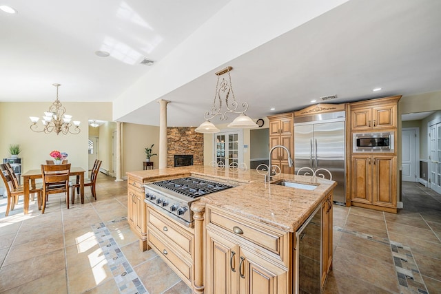 23 Antona Blvd, Centereach, NY 11720 - kitchen featuring built in appliances, wine cooler, a fireplace, a chandelier, and light stone countertops