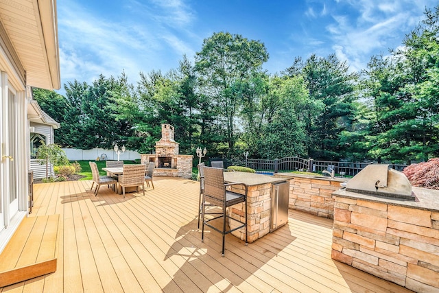 23 Antona Blvd, Centereach, NY 11720 - deck with an outdoor stone fireplace, an outdoor kitchen, a fenced backyard, and view of wooded area