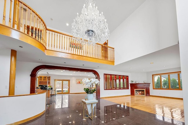 64-16 211th St, Bayside, NY 11364 - living room featuring a high ceiling, arched walkways, granite floors, a lit fireplace, and a chandelier