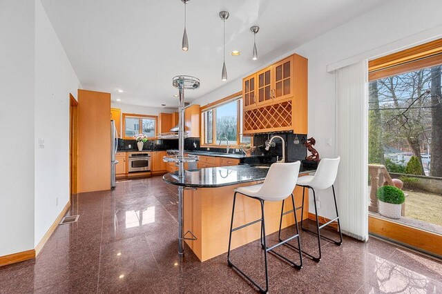 64-16 211th St, Bayside, NY 11364 - kitchen with granite tiled floors, a peninsula, stainless steel appliances, tasteful backsplash, and recessed lighting