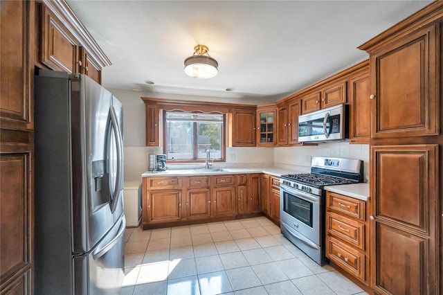 189 Stanton Blvd, Uniondale, NY 11553 - kitchen with stainless steel appliances, light countertops, light tile patterned floors, brown cabinets, and glass insert cabinets
