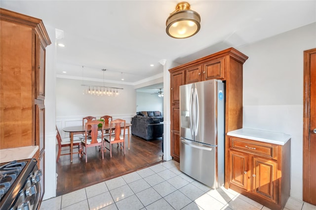 189 Stanton Blvd, Uniondale, NY 11553 - kitchen with stainless steel fridge with ice dispenser, gas range oven, brown cabinetry, light tile patterned floors, and wainscoting