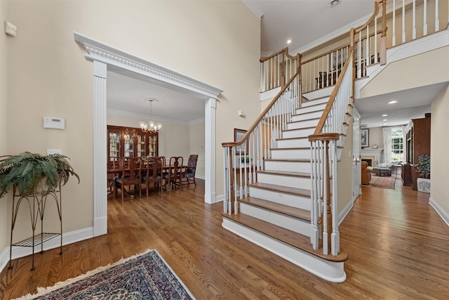 41 Carlton Dr, Mount Kisco, NY 10549 - stairway with wood finished floors, crown molding, a chandelier, a fireplace, and a high ceiling