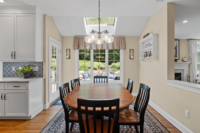 41 Carlton Dr, Mount Kisco, NY 10549 - dining area with light wood-style flooring, a chandelier, healthy amount of natural light, vaulted ceiling, and a fireplace