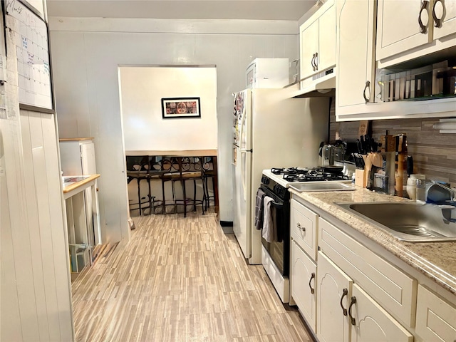 44 Waldo Ave, East Rockaway, NY 11518 - kitchen featuring gas range, light wood-style floors, under cabinet range hood, light countertops, and white cabinetry