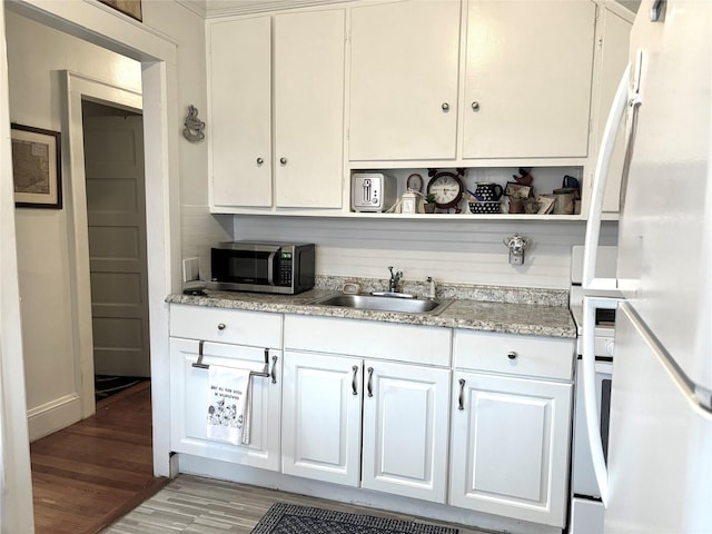44 Waldo Ave, East Rockaway, NY 11518 - kitchen featuring stainless steel microwave, freestanding refrigerator, open shelves, light wood-style flooring, and white cabinetry