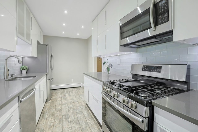 13 Darian Ct Unit 2B, Pomona, NY 10970 - kitchen featuring appliances with stainless steel finishes, a baseboard heating unit, white cabinetry, backsplash, and light wood-style floors