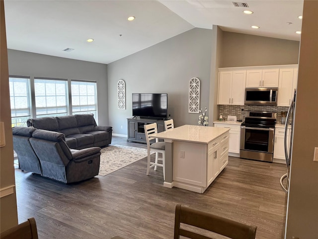 310 Narragansett Villas Dr, Lindenhurst, NY 11757 - kitchen featuring stainless steel appliances, open floor plan, white cabinetry, lofted ceiling, and a kitchen island