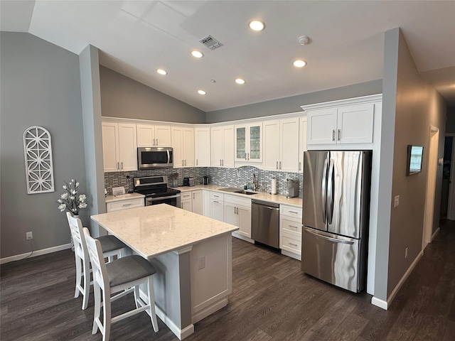 310 Narragansett Villas Dr, Lindenhurst, NY 11757 - kitchen featuring appliances with stainless steel finishes, vaulted ceiling, dark wood-style flooring, tasteful backsplash, and white cabinets