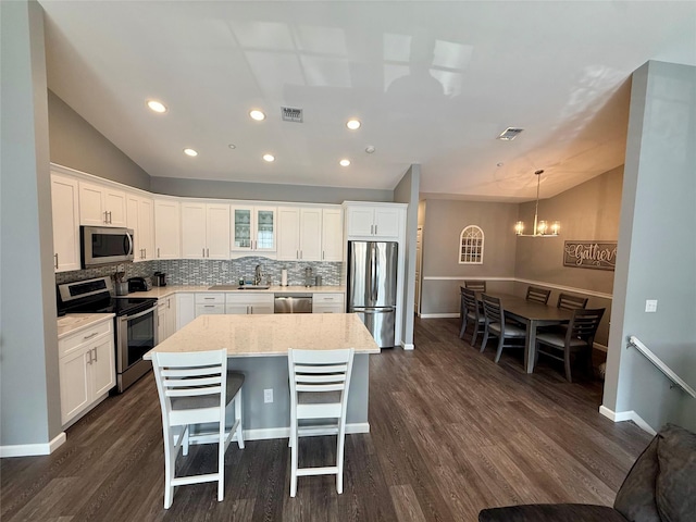 310 Narragansett Villas Dr, Lindenhurst, NY 11757 - kitchen with appliances with stainless steel finishes, lofted ceiling, tasteful backsplash, a chandelier, and dark wood finished floors