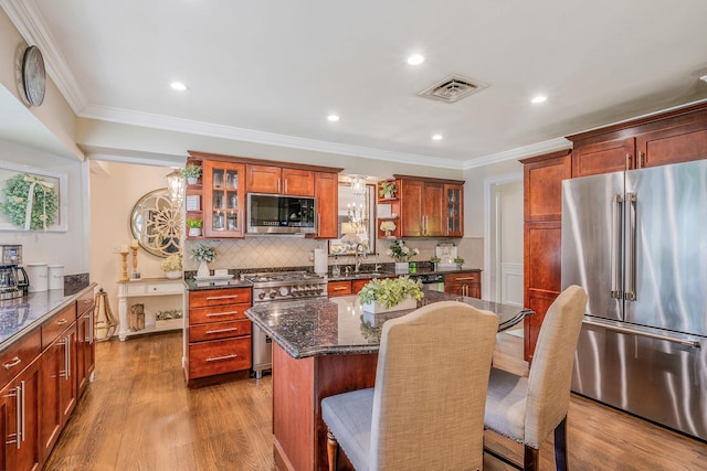 6 Pine St N, Lake Grove, NY 11755 - kitchen featuring high quality appliances, wood finished floors, a kitchen bar, decorative backsplash, and glass insert cabinets