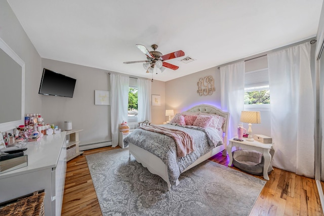 6 Pine St N, Lake Grove, NY 11755 - bedroom featuring baseboard heating, wood finished floors, and ceiling fan