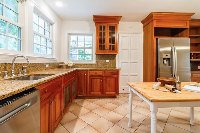 50 Overlook Dr, Chappaqua, NY 10514 - kitchen featuring stainless steel appliances, light stone countertops, tasteful backsplash, glass insert cabinets, and brown cabinetry