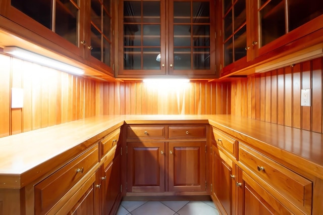 50 Overlook Dr, Chappaqua, NY 10514 - kitchen with light tile patterned floors, light countertops, glass insert cabinets, brown cabinets, and wooden walls
