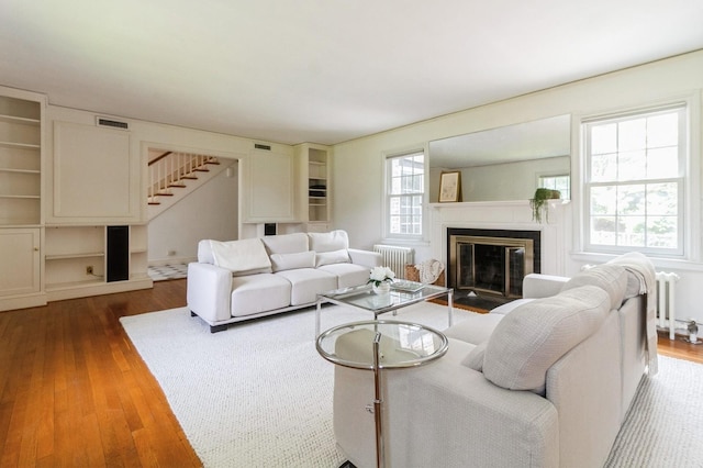 50 Overlook Dr, Chappaqua, NY 10514 - living room with radiator, wood-type flooring, stairway, and a fireplace with flush hearth