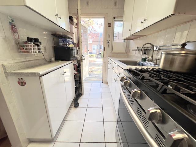 220-34 67th Ave Duplex, Unit Duplex, Bayside, NY 11364 - kitchen featuring stainless steel gas stove, light countertops, tasteful backsplash, white cabinets, and light tile patterned floors