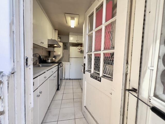 220-34 67th Ave Duplex, Unit Duplex, Bayside, NY 11364 - kitchen with freestanding refrigerator, extractor fan, light tile patterned floors, white cabinetry, and light countertops