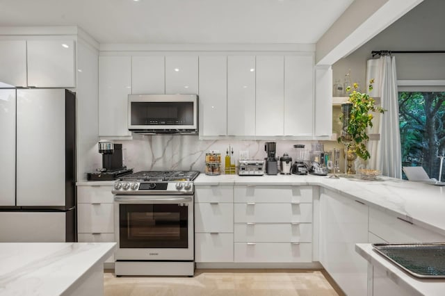 545 Hampton Rd Unit 16, Southampton, NY 11968 - kitchen with appliances with stainless steel finishes, modern cabinets, white cabinets, and light stone countertops
