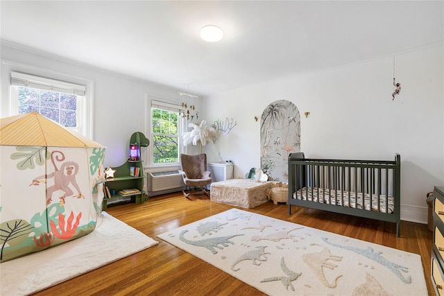 121 Overlook Cir, New Rochelle, NY 10804 - bedroom featuring ornamental molding, wood finished floors, a wall mounted AC, a crib, and a chandelier