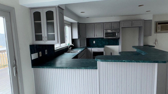 127 Forest Ave, Massapequa, NY 11758 - kitchen with stainless steel microwave, gray cabinetry, a wall mounted air conditioner, glass insert cabinets, and a peninsula