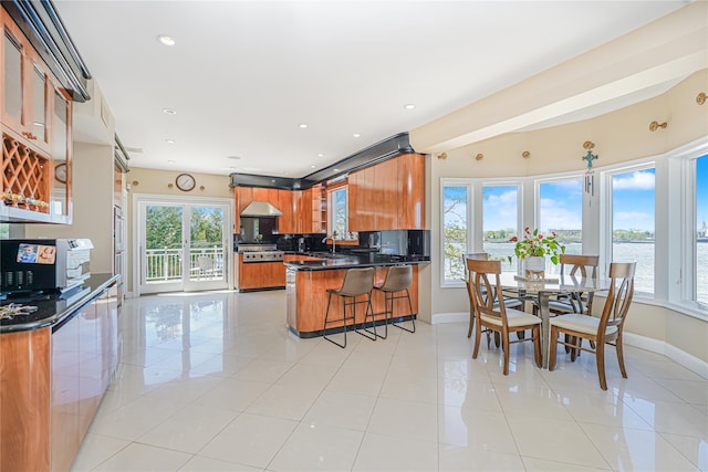 30 Aviva Ct, Staten Island, NY 10307 - kitchen with brown cabinets, a peninsula, dark countertops, glass insert cabinets, and a breakfast bar area