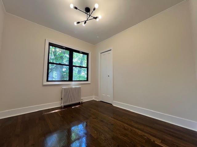 4118 Hill Ave, Bronx, NY 10466 - empty room featuring radiator heating unit, dark wood-style floors, a chandelier, and ornamental molding
