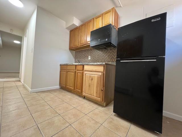 4118 Hill Ave, Bronx, NY 10466 - kitchen with freestanding refrigerator, light tile patterned floors, backsplash, and brown cabinetry