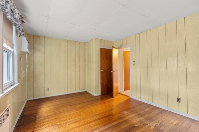 72 Putnam Ave, Valley Stream, NY 11580 - spare room with hardwood / wood-style floors, radiator, an AC wall unit, and wooden walls