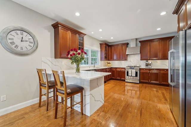 10 Willow Dr, Suffern, NY 10901 - kitchen featuring appliances with stainless steel finishes, a peninsula, wall chimney range hood, light wood finished floors, and tasteful backsplash