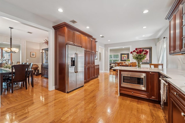 10 Willow Dr, Suffern, NY 10901 - kitchen with appliances with stainless steel finishes, light wood-style floors, a chandelier, light stone counters, and a peninsula