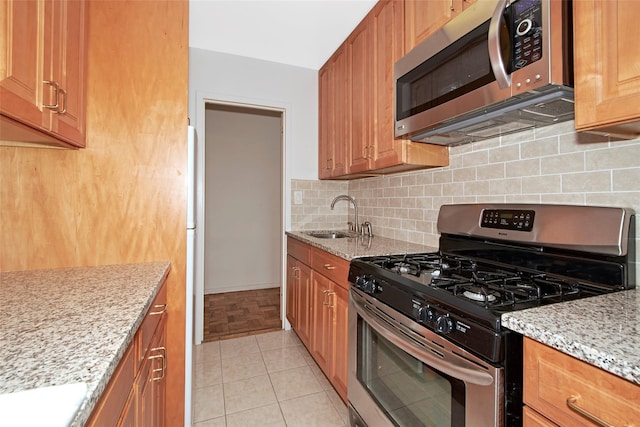 33 Barker Ave Unit 6K, White Plains, NY 10601 - kitchen featuring stainless steel appliances, backsplash, light stone counters, and brown cabinetry