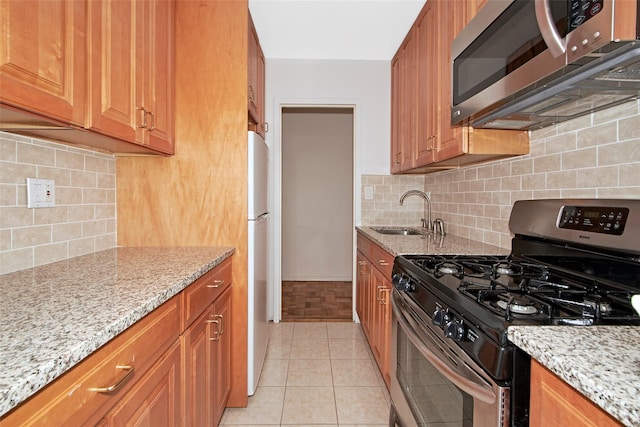 33 Barker Ave Unit 6K, White Plains, NY 10601 - kitchen featuring appliances with stainless steel finishes, light stone countertops, backsplash, and brown cabinetry